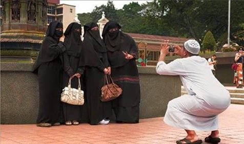 man taking pic of hijabbed women